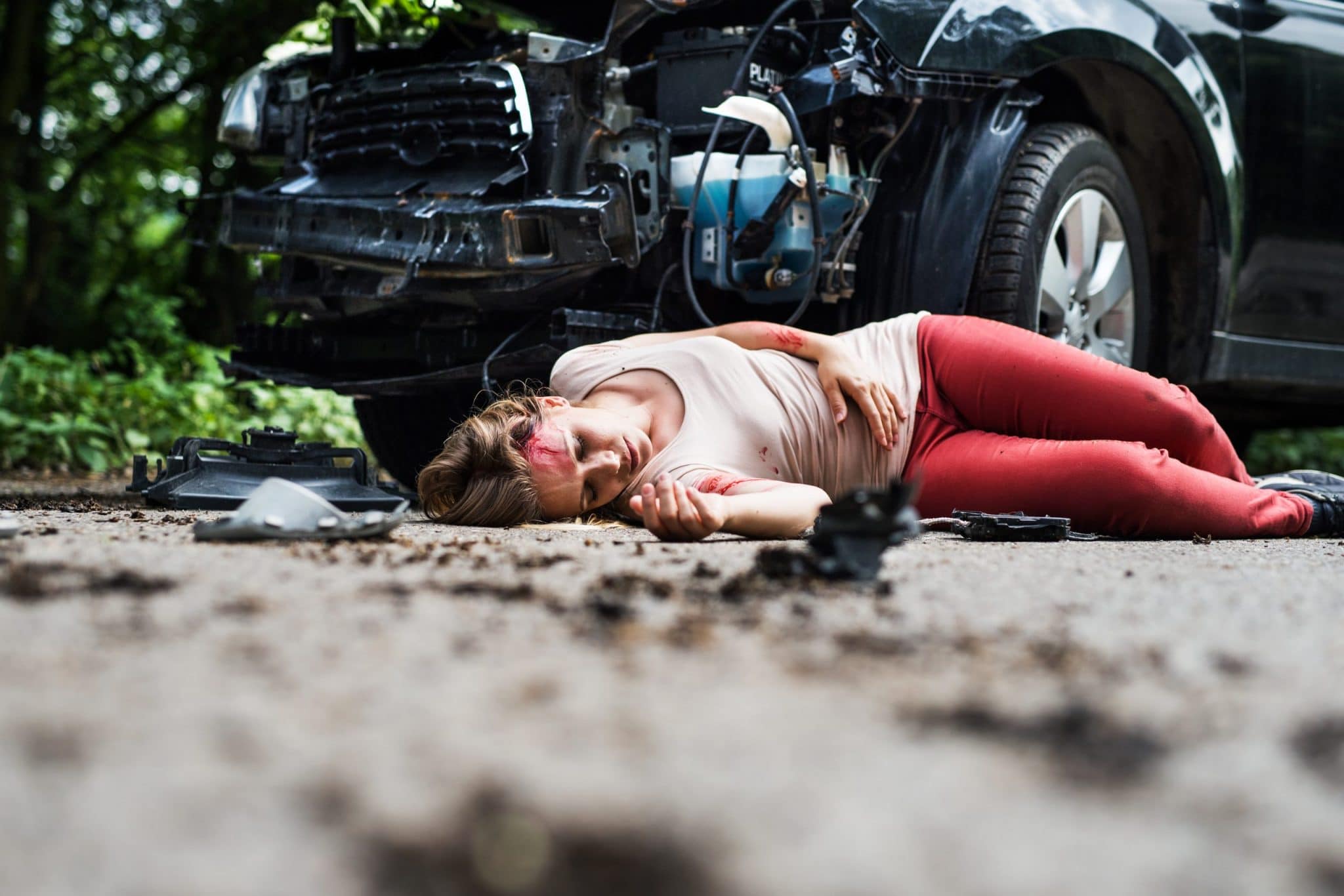 Young injured woman lying on the road after a car accident, unconscious. 